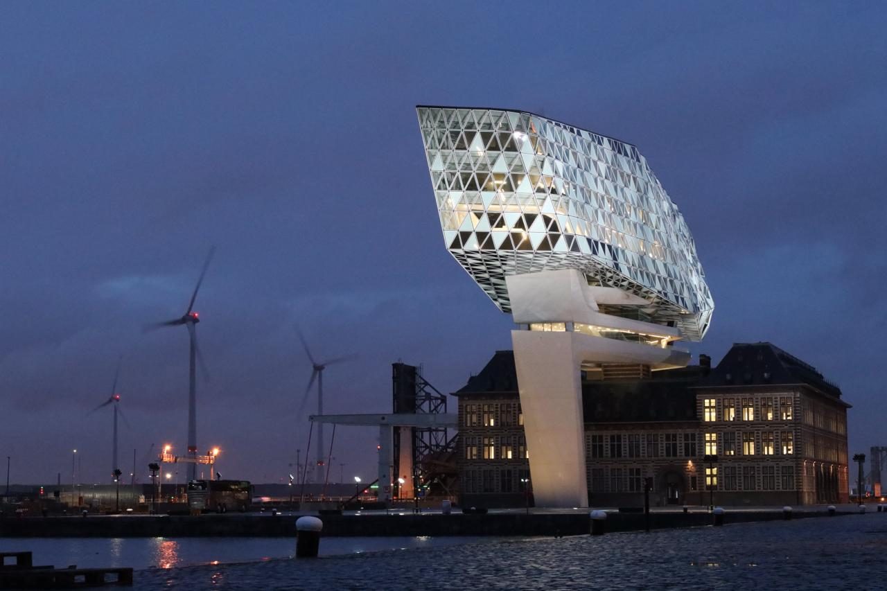 Het Havenhuis van Zaha Hadid bij avondlicht, met de glazen kristalvorm boven op het oude brandweergebouw