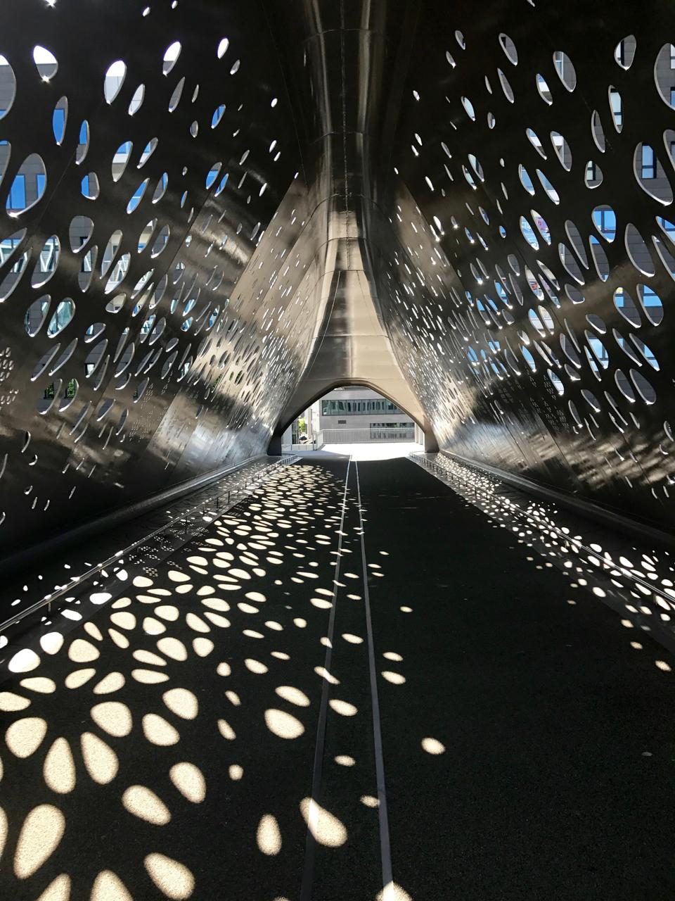 De Parkbrug — een geperforeerde stalen loopbrug die lichtvlekken op het wegdek werpt